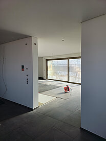 Geräumiger Raum mit einem großen Fenster, das Tageslicht hereinlässt, und einem großzügigen Bodenbereich